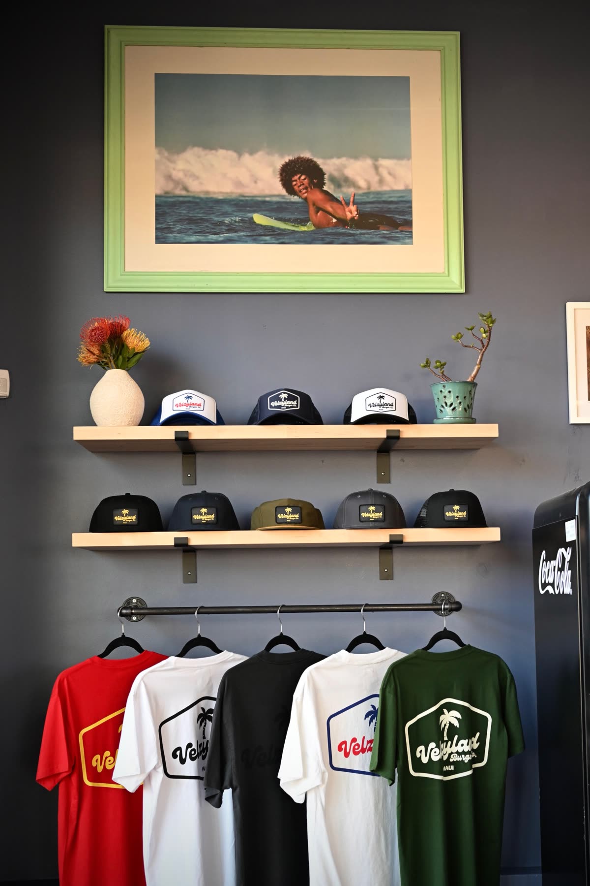 The merch wall: hats, tees, surf print